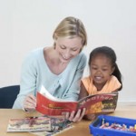 Teacher helping young girl read